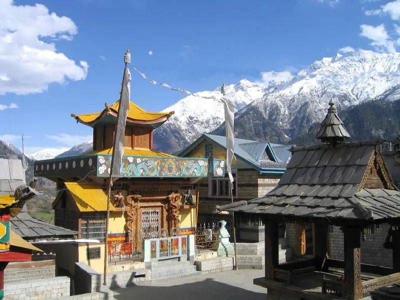 Kinnauri temple with prayer flags and snow-capped peaks in Sangla Valley, Kinnaur